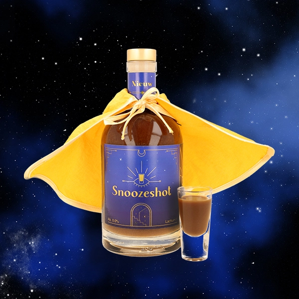 Snooze Shot bottle with chocolate-colored liquid, blue label, and a yellow cloak around it, with a shot glass in space.