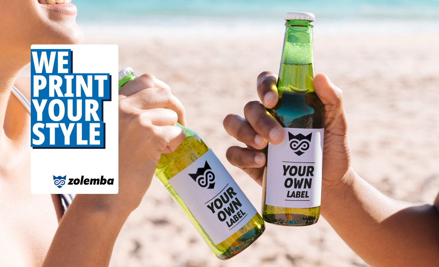 Dos manos chocan botellas de cerveza con etiquetas personalizadas en una playa con un banner de Zolemba que dice 'Imprimimos Tu Estilo' a la izquierda.